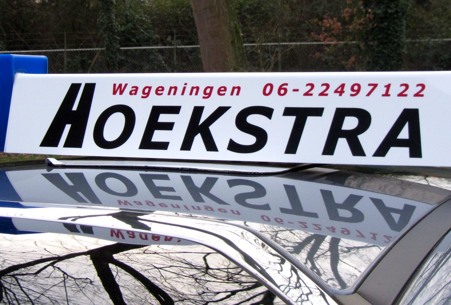 Daklicht op de lesauto van Autorijschool Hoekstra in Wageningen, met blauw L-bord en telefoonnummer